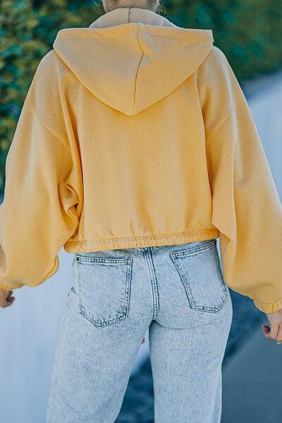 a woman wearing a yellow hoodie and jeans