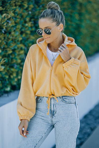 a woman wearing a yellow jacket and jeans