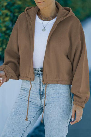 a woman wearing a brown jacket and jeans