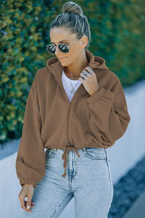 a woman wearing a brown jacket and sunglasses