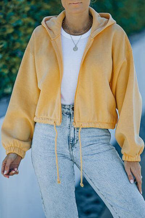 a woman wearing a yellow jacket and jeans