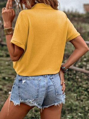 a woman wearing a yellow shirt and denim shorts