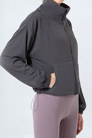 a woman wearing a gray jacket and purple pants