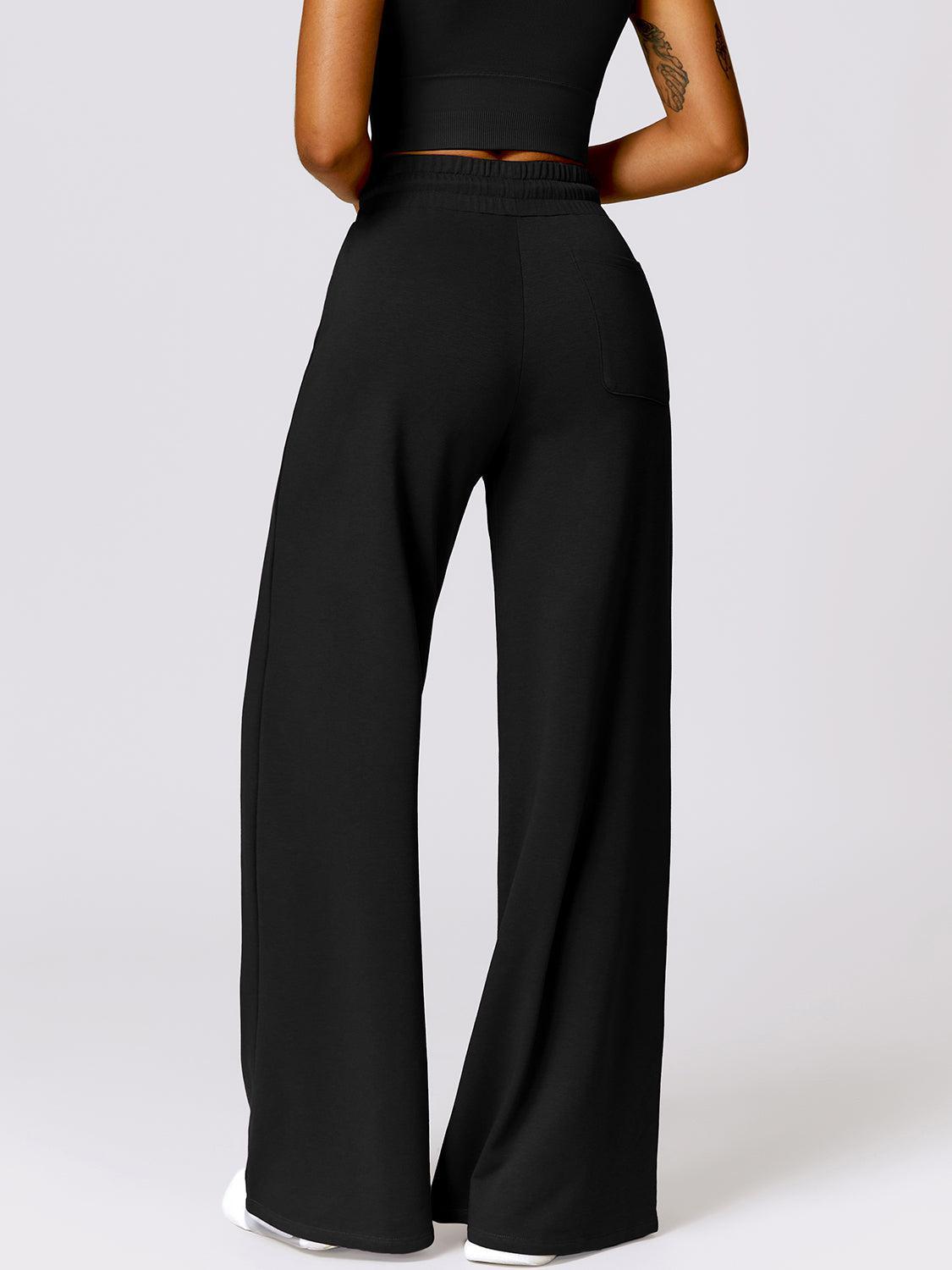 a woman wearing a black crop top and wide legged pants
