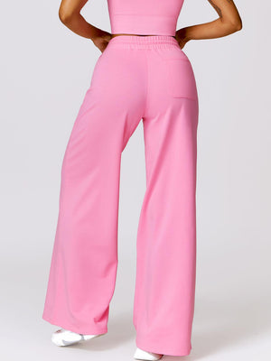 a woman in a pink top and wide pants