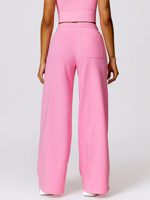 a woman in a pink crop top and wide legged pants