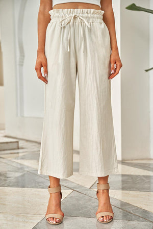 a woman standing on a tiled floor wearing white pants