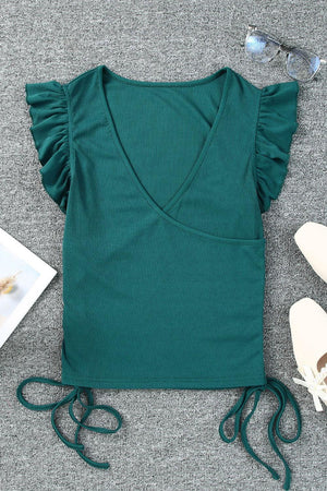 a green top with a pair of white shoes next to it