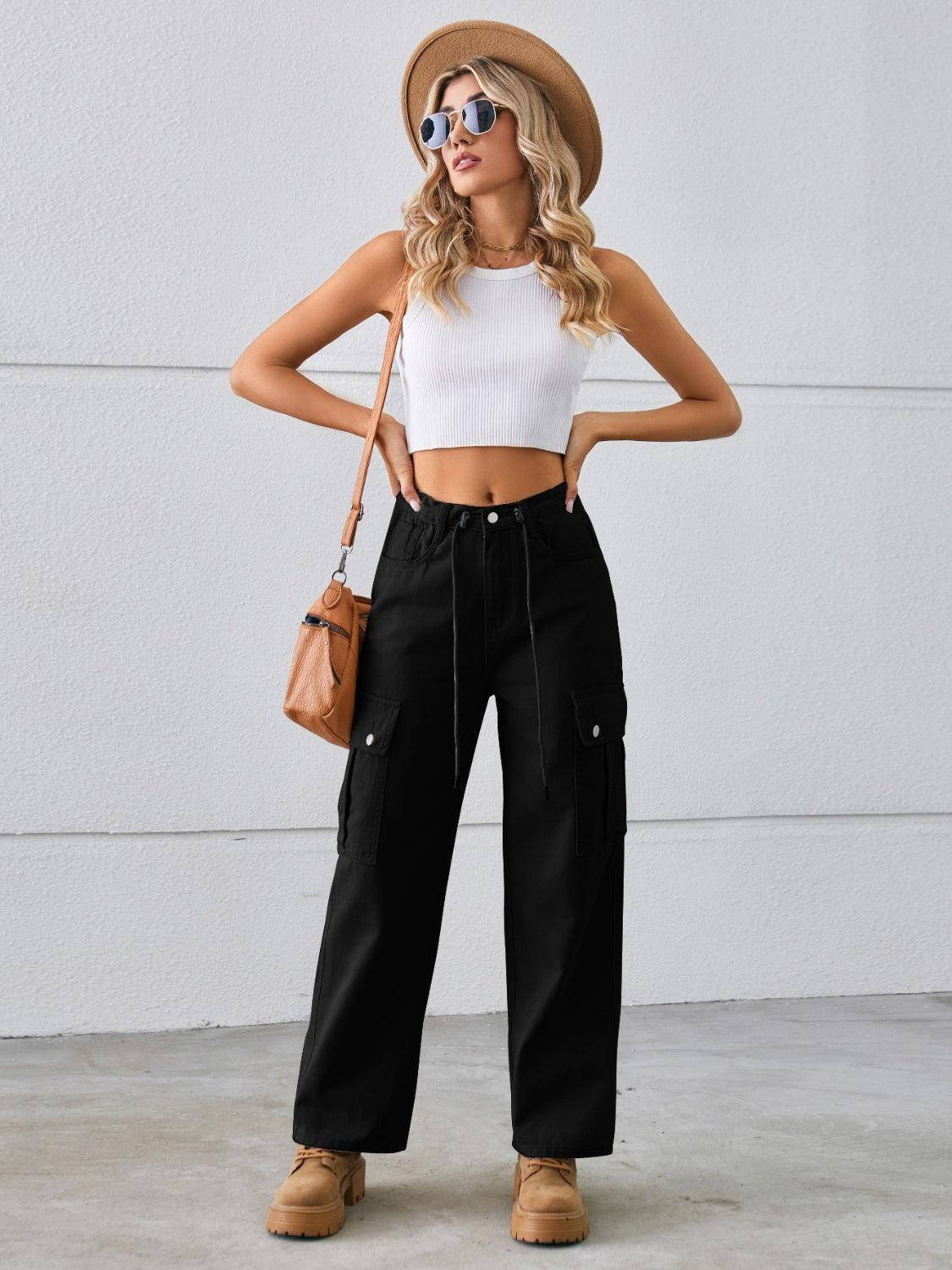 a woman wearing a white crop top and black cargo pants