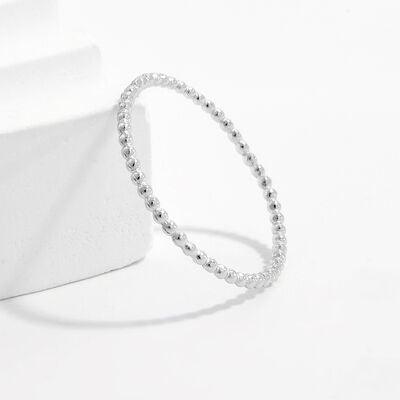a silver beaded ring sitting on top of a white surface