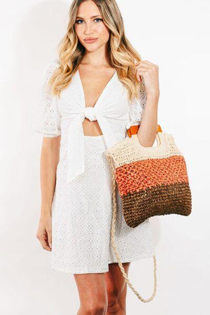 a woman in a white dress holding a brown and orange purse