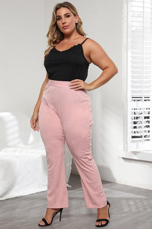 a woman in a black top and pink pants