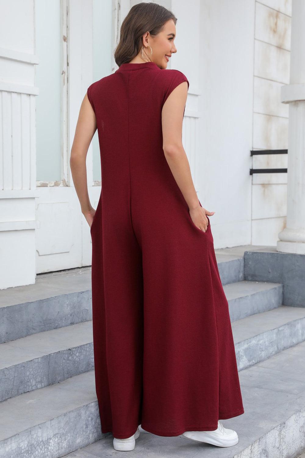 a woman in a red jumpsuit standing on steps