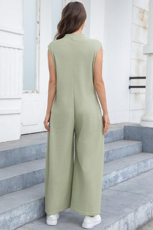 a woman in a green jumpsuit standing on steps