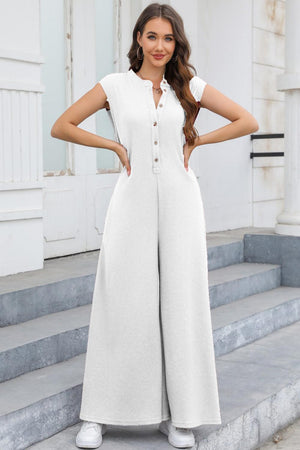 a woman wearing a white jumpsuit standing on steps