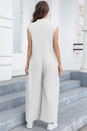 a woman in a white jumpsuit standing on steps