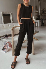 a woman standing in a living room wearing a black top and pants