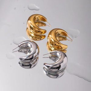 a pair of gold and silver earrings sitting on top of a table