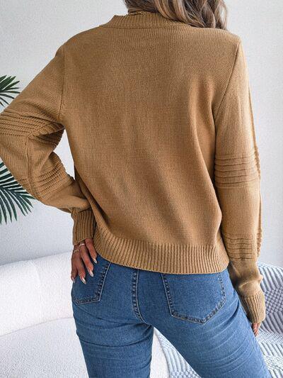 a woman wearing a tan sweater and jeans