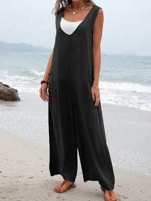 a woman standing on a beach wearing a black and white jumpsuit