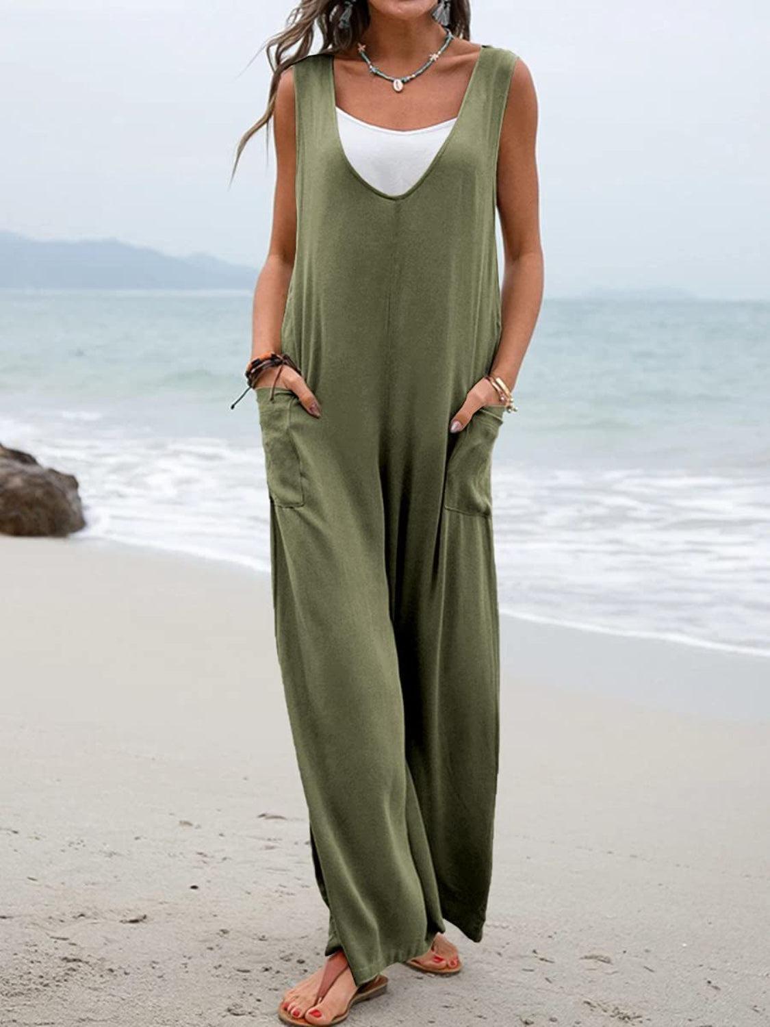 a woman standing on a beach wearing a green jumpsuit