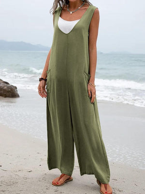 a woman standing on a beach wearing a green jumpsuit