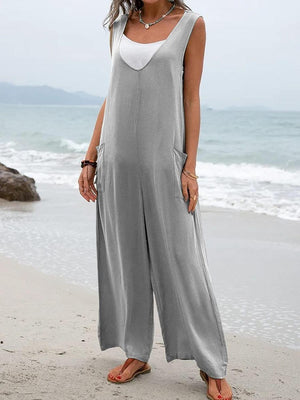 a woman standing on a beach wearing a gray jumpsuit