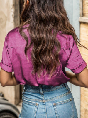 a woman with long brown hair wearing a pink shirt