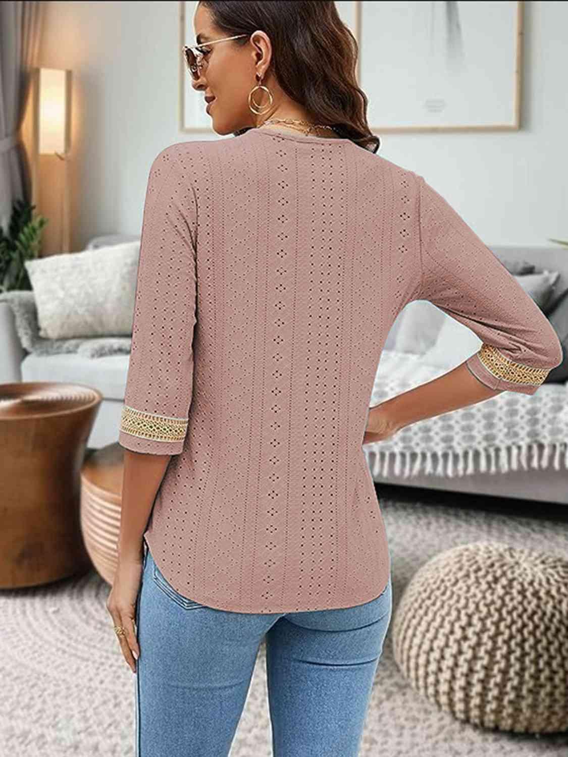 a woman standing in a living room wearing a pink sweater