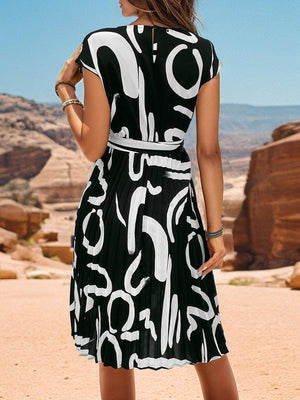 a woman in a black and white dress standing in the desert