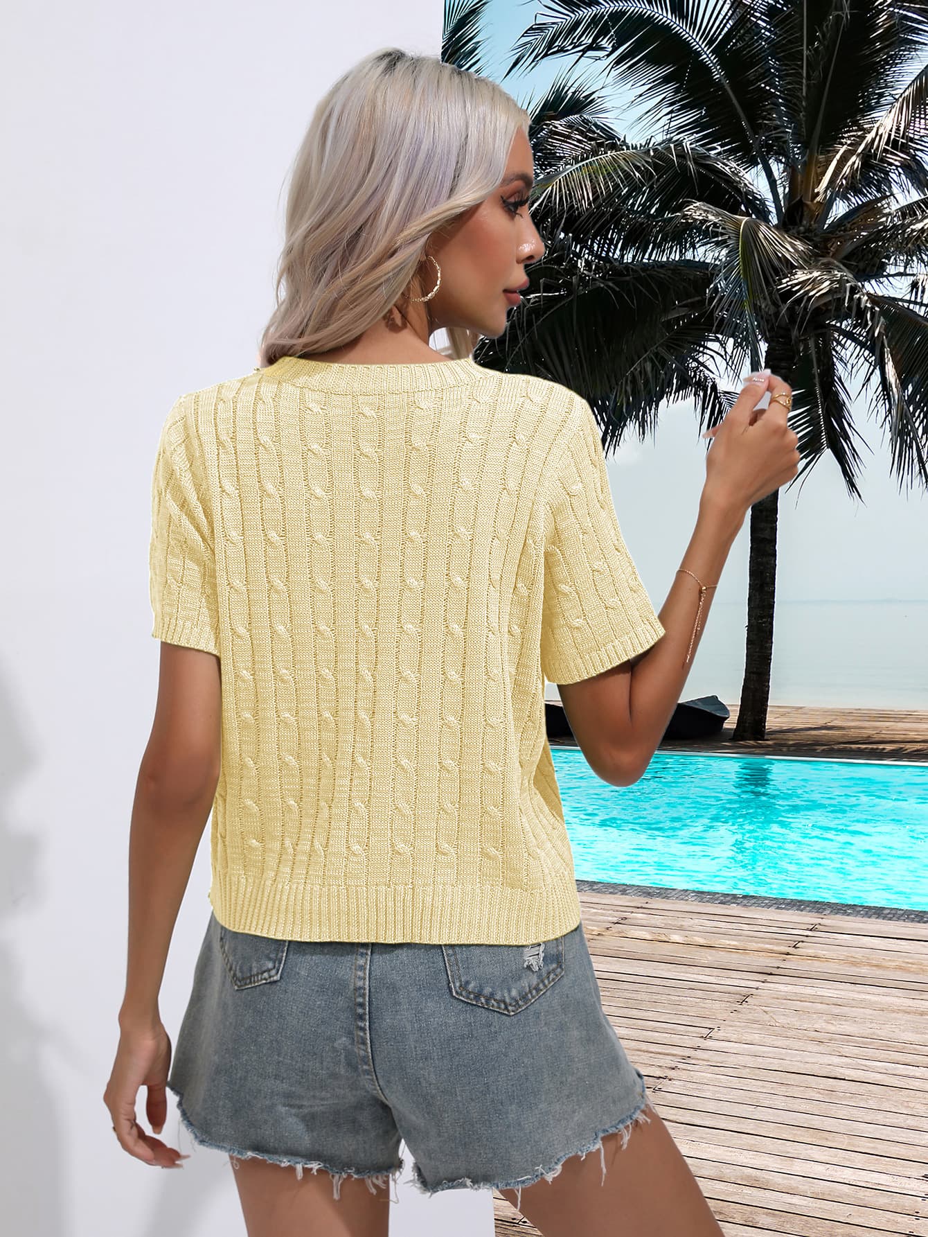 a woman standing next to a pool wearing a yellow sweater