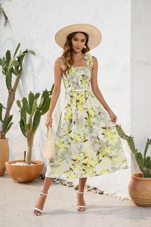 a woman in a dress and hat standing in front of a cactus