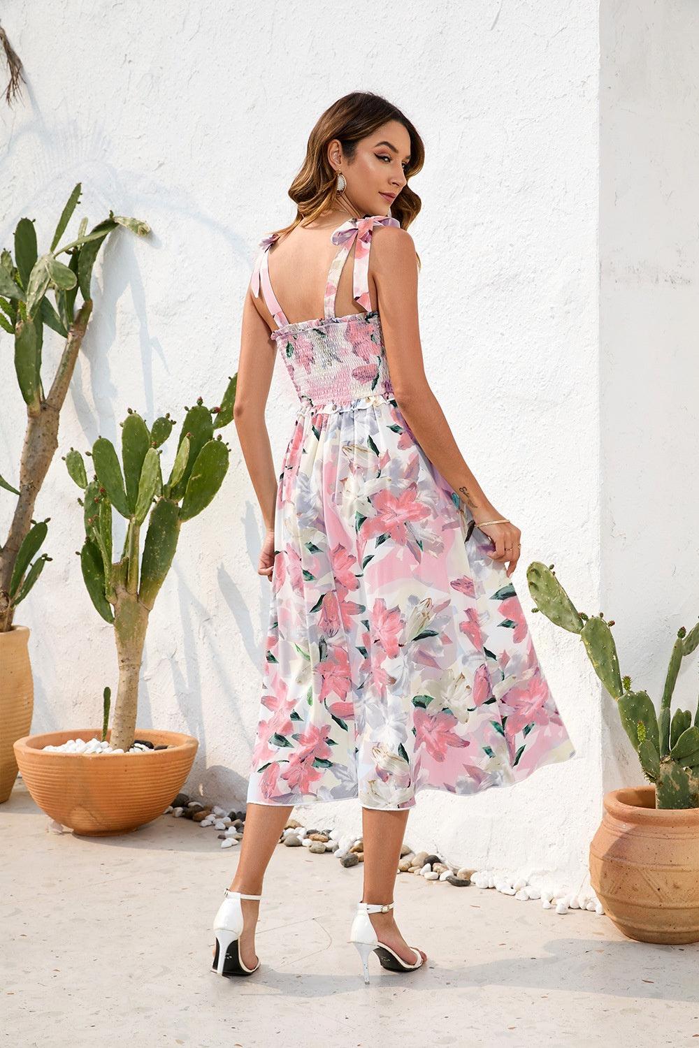 a woman in a floral print dress standing in front of a cactus