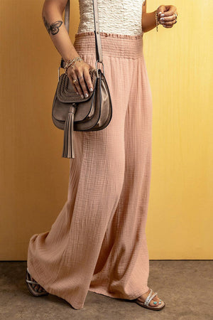 a woman in a white top and pink pants holding a purse