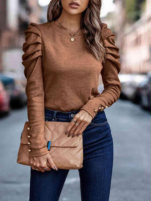 a woman wearing a brown sweater and jeans