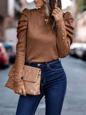 a woman wearing a brown sweater and jeans