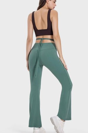 a woman in a crop top and green pants