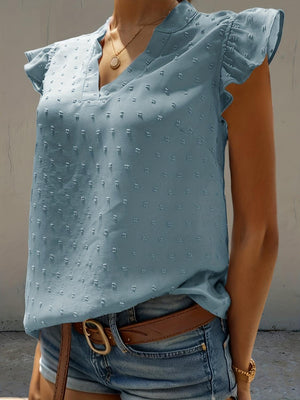 a woman wearing a blue blouse and denim shorts