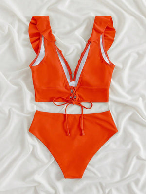 a woman in an orange swimsuit laying on a bed
