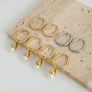 five pairs of gold and silver earrings on a stone slab