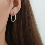 a woman wearing a pair of silver hoop earrings