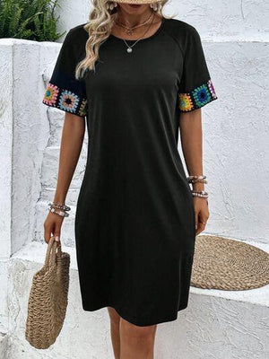 a woman wearing a black dress with colorful embroidered sleeves