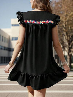 a woman walking across a parking lot wearing a black dress