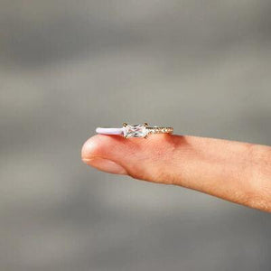 a person's hand holding a tiny diamond ring