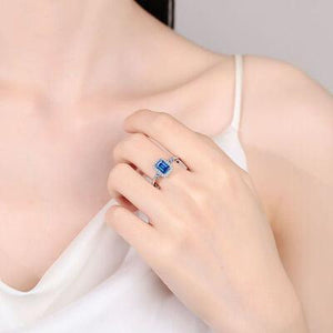 a woman wearing a ring with a blue stone