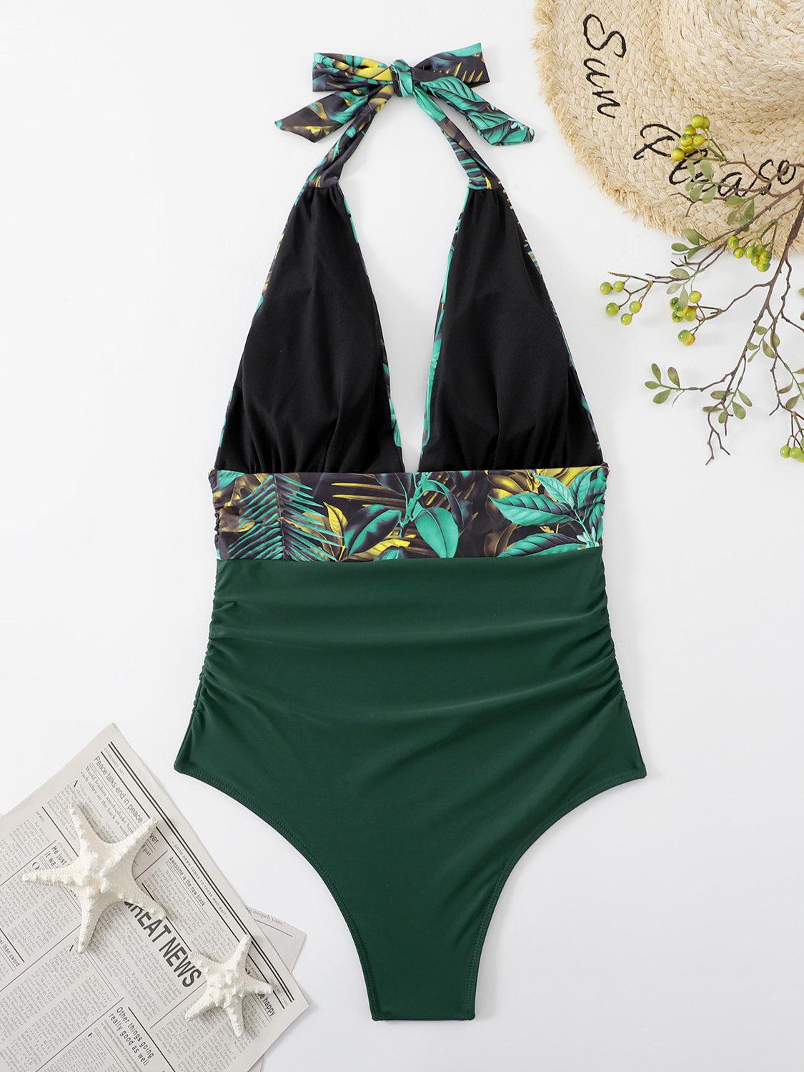 a green and black one piece swimsuit next to a hat