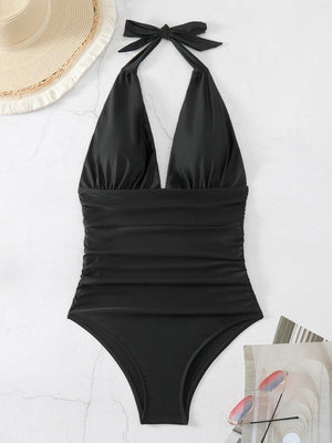 a black one piece swimsuit next to a straw hat