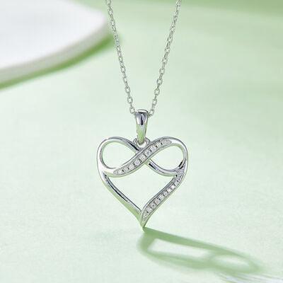 a heart shaped pendant with diamonds on a green surface