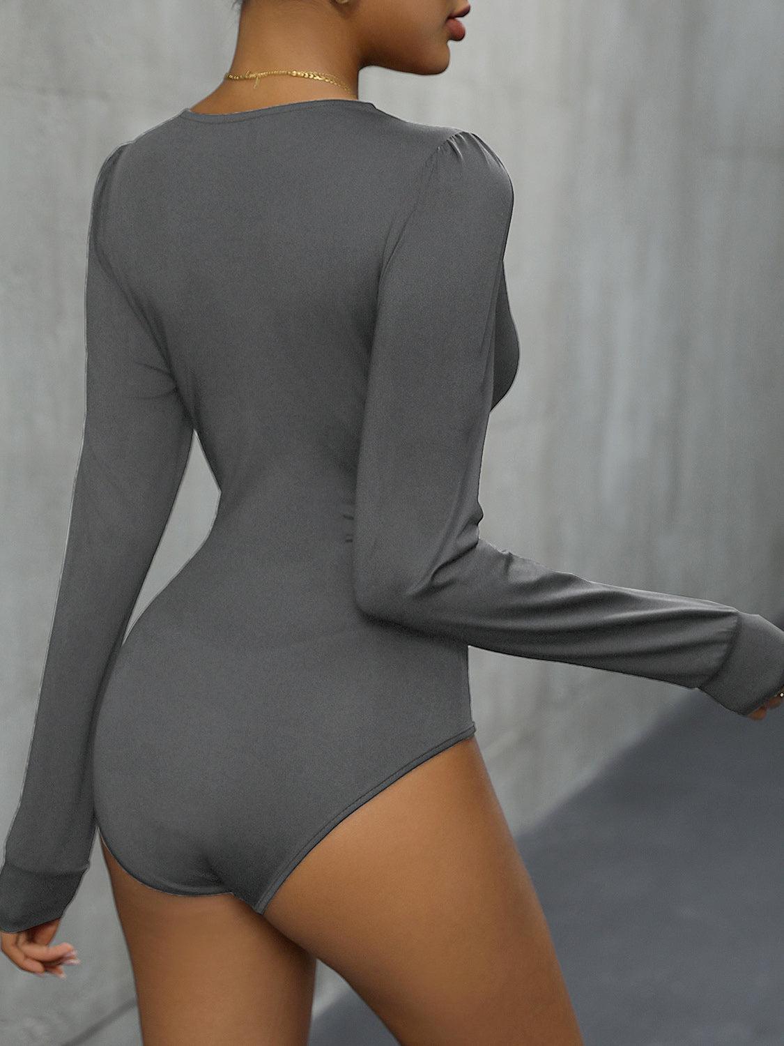 a woman in a gray bodysuit is posing for the camera