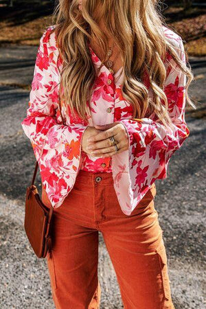 a woman with long hair wearing an orange pants and a floral shirt